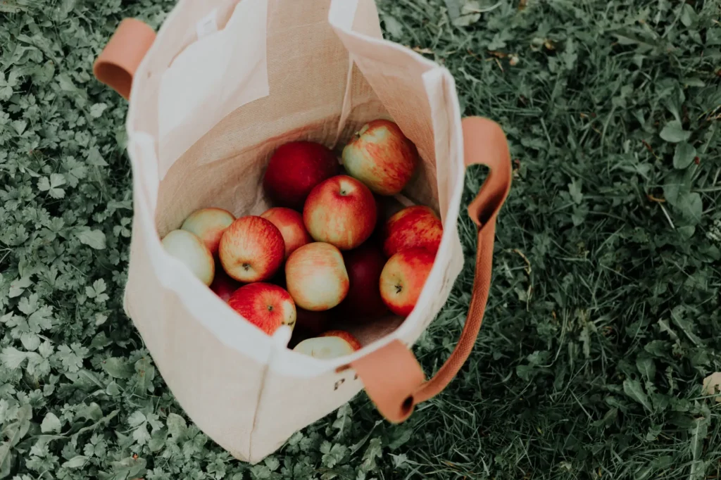 A reusable shopping bag filled with apples